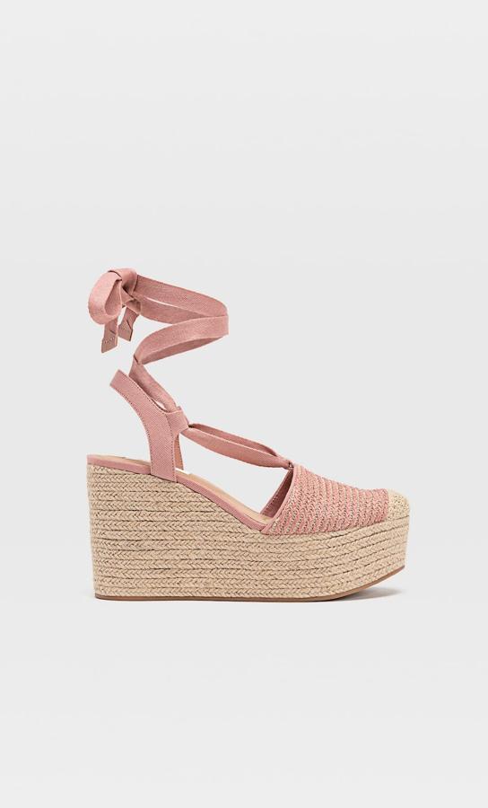 En tu armario no pueden faltar unas cuñas de yute como estas en color rosa. Con cinta para atar al tobillo, tiene un precio de 15,99 euros.