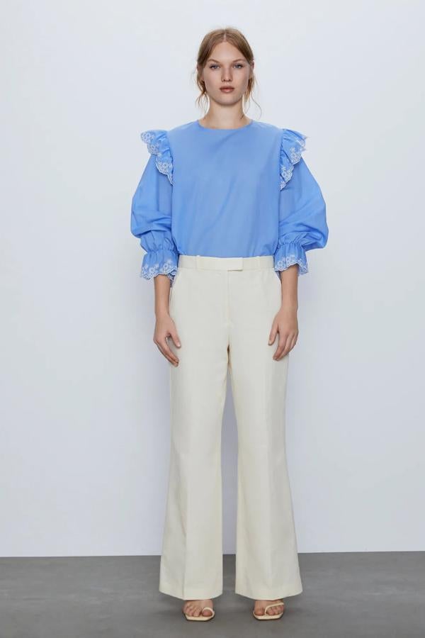 En color azul, esta blusa con cuello redondo y detalle de volantes con bordados perforados tiene un precio de 9,99 euros.