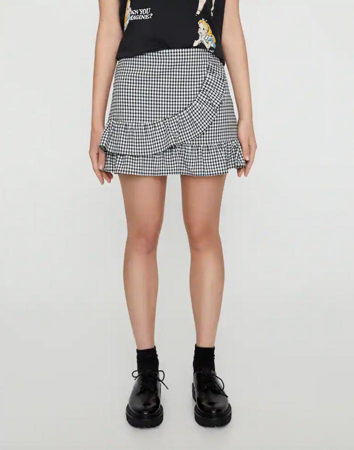 Esta falda pantalón con parte delantera tipo parteo asimétrico es de Pull&Bear y viene con estampado de cuadro vichy en tonos blancos y negros y detalle de volantes. Cuesta 17,99 euros y solo queda en la talla L.