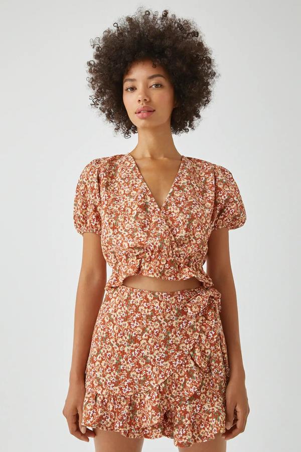 Estampada con pequeñas flores, y disponible en varios colores, esta blusa estampada con escote de pico cruzado cuenta con detalle de goma en el bajo y tiene un precio de 17,99 euros.