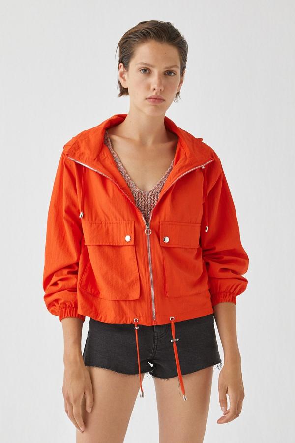 En tejido de nylon, esta cazadora disponible en varios colores lisos cuenta con capucha y bolsillos con botones automáticos. Se cierra con cremallera y tiene un precio de 19,99 euros.