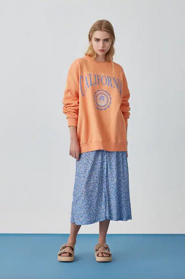 Si lo tuyo son los tonos cálidos, en Pull&Bear hemos encontrado esta bonita sudadera en color mandarina, con manga larga y cuello redondo. Con terminaciones en canalé en los puños, el bajo y el cuello, cuesta 19,99 euros y solo queda entre las tallas XXS y M, y la última se está agotando.