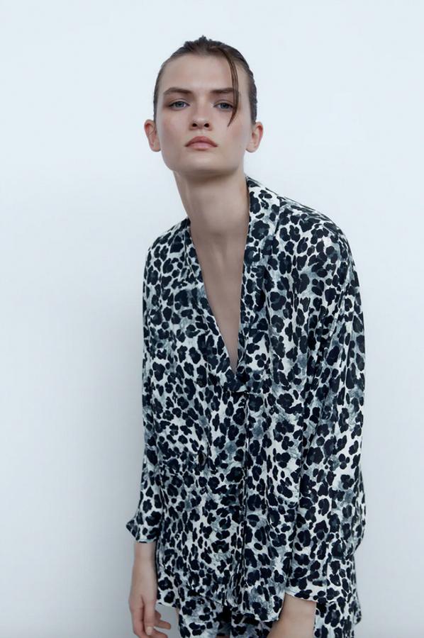 Esta blusa fluida con escote de pico con solapa y manga larga es de Zara y viene con cierre frontal con botones. Con estampado en tonos negros y grises, tiene un precio de 25,95 euros y está disponible entre las tallas XS y L.