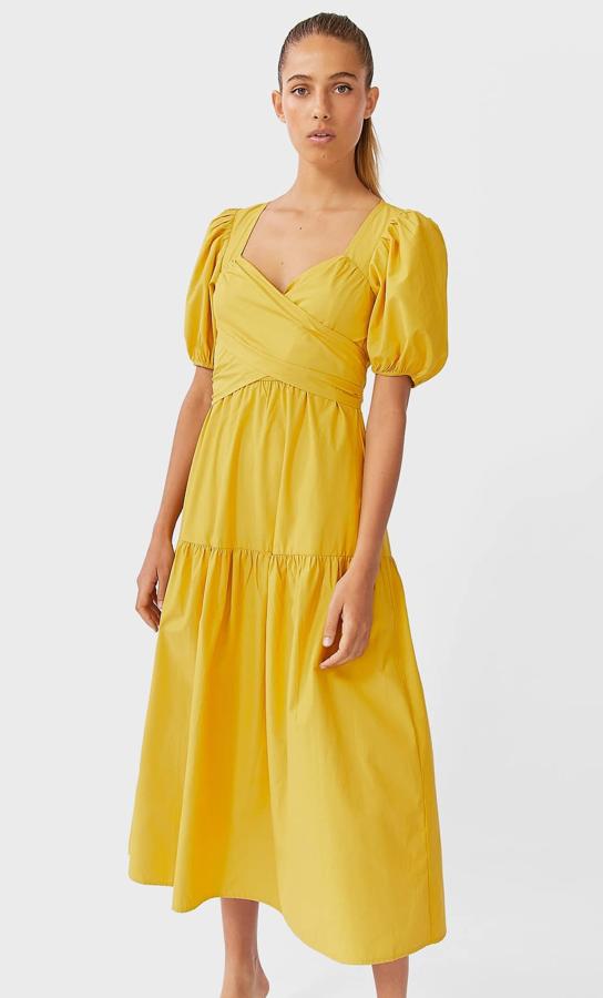 En color mostaza, este vestido midi de escote de pico y manga corta abullonada cuenta con detalle de lazada cruzada en el pecho. Es de Stradivarius y tiene un precio de 29,99 euros.