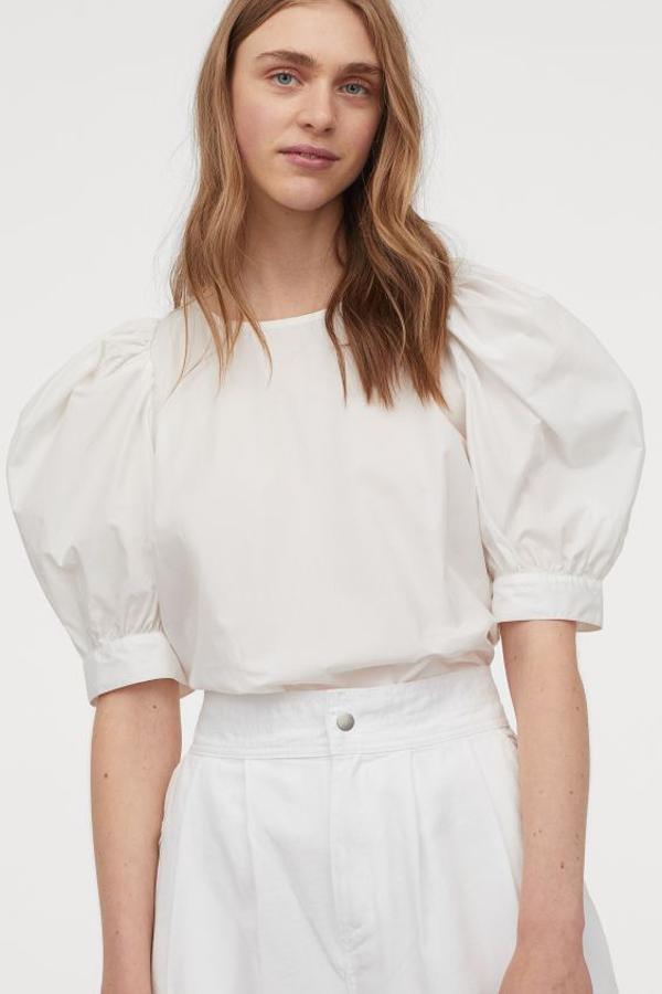Confeccionada en algodón vaporoso con cuello redondo, cierre de lágrima con botón oculto en la nuca y mangas cortas abullonadas con puños finos abotonados, esta blusa de H&M tiene un precio de 14,99 euros y está disponible entre las tallas XS y XXL.