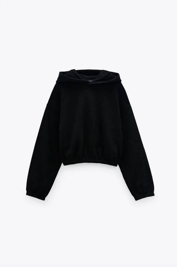 Diseño corto en color negro para esta sudadera de Zara con capucha, manga larga y acabados en elástico. Cuesta 15,95 euros y está disponible entre las tallas S y XL.