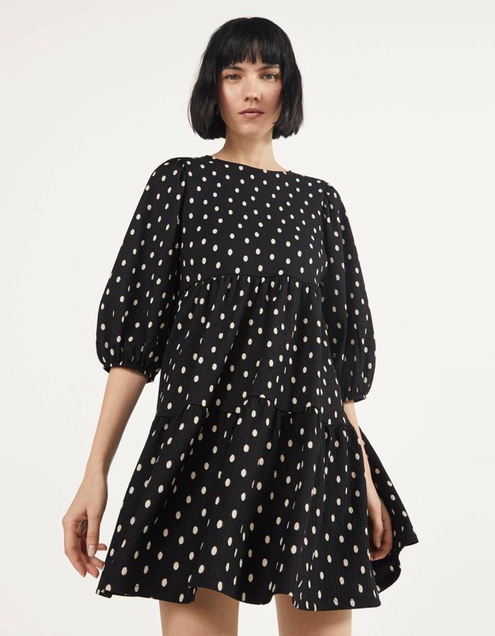 Diseño babydoll para este vestido corto en color negro con lunares a contraste en blanco. Tiene el cuello redondo, la manga tres cuartos abullonada y el bajo con volumen. Es de Bershka, cuesta 17, 99 euros y está disponible únicamente en la talla S.