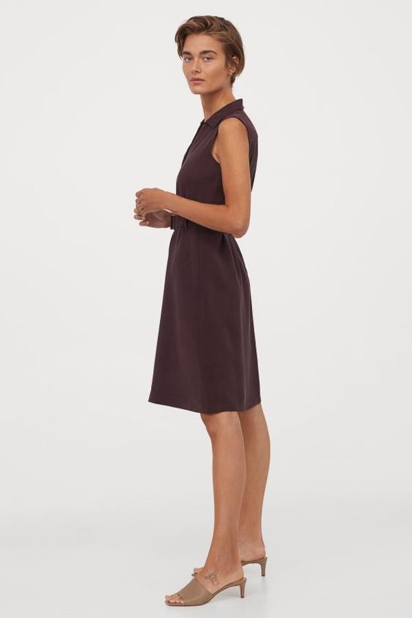 Este bonito vestido en lila oscuro sin mangas viene con cuello camisero , abertura en V y cinturón con anillas de metal. Tiene un precio de 29,99 euros y está disponible entre las tallas 32 y 50 y en color crema.