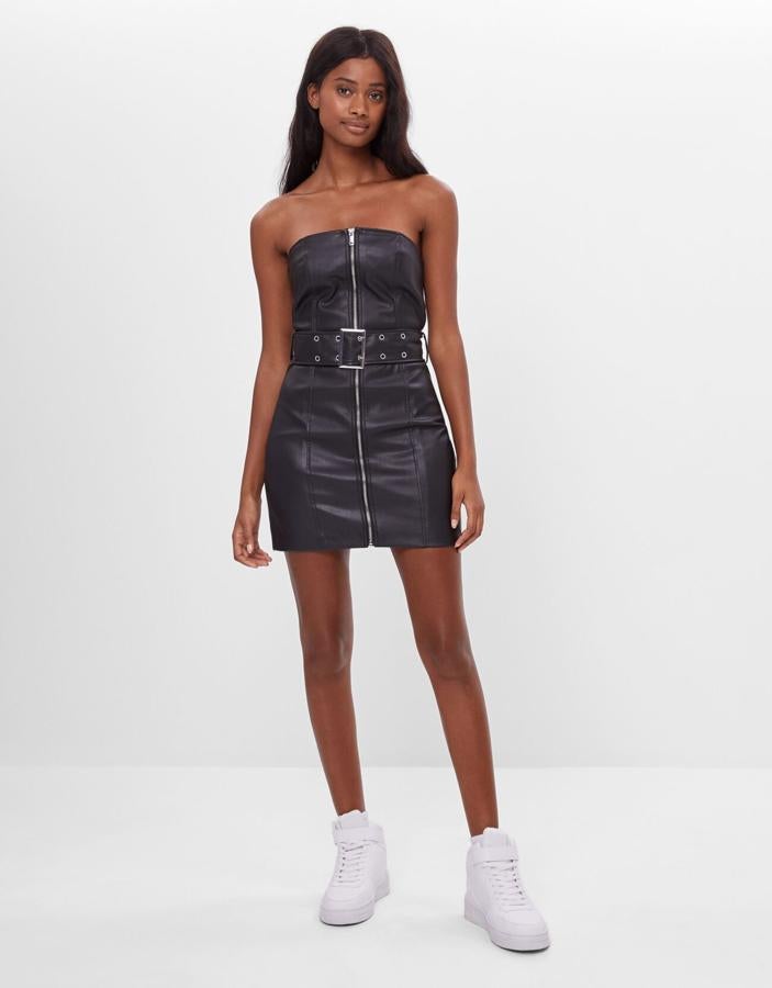 Minivestido de efecto piel con escote palabra de honor, cierre de cremallera frontal y cinturón ancho, de Bershka (25,99 €).