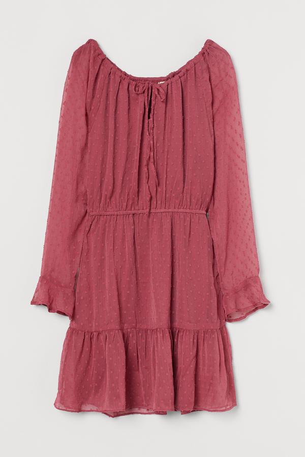 En color rosa, este vestido corto en gasa plumeti vaporosa con efecto arrugado cuenta con escote amplio con cordón de ajuste. Con volante en los puños y en el bajo, tiene un precio de 19,99 euros.