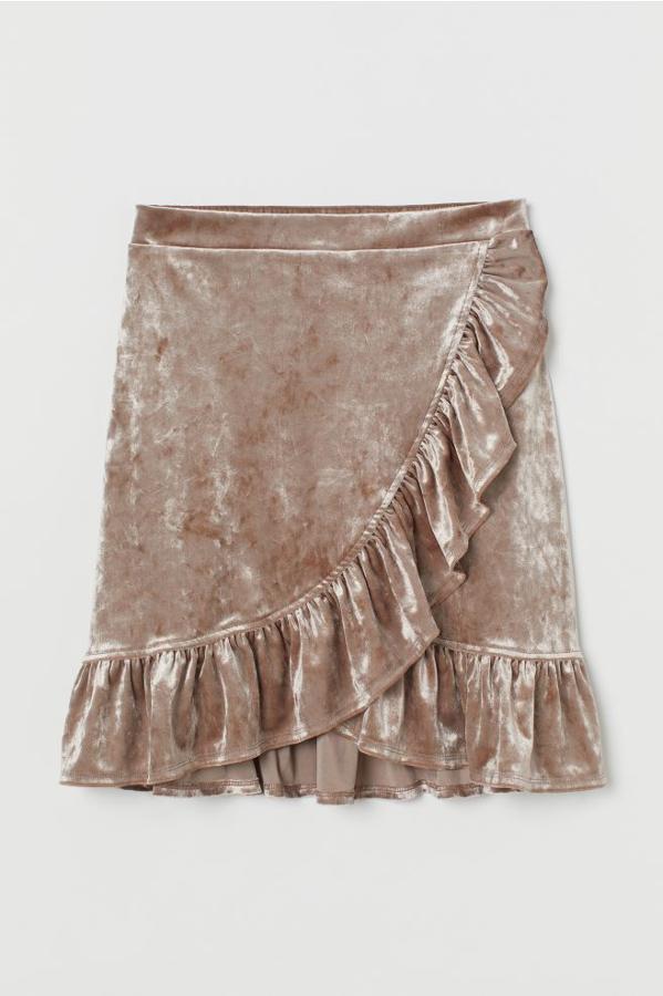 En velour con brillo, esta falda en terciopelo arrugado de H&M viene con talle alto con elástico en la parte posterior de la pretina y frente cruzado cosido con ribete de volantes. Tiene un precio de 19,99 euros y está disponible entre las tallas XS y XL.