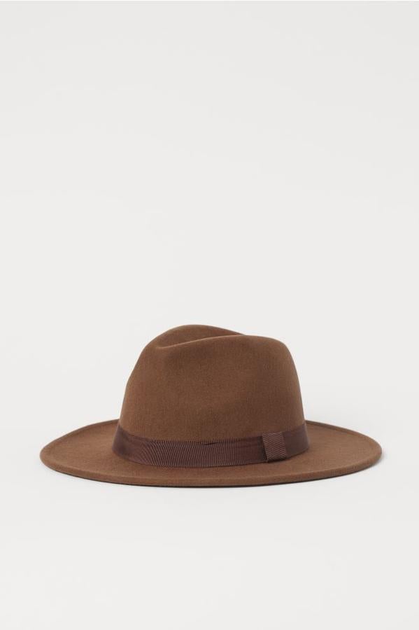 Confeccionado en lana de fieltro con cinta a tono alrededor de la copa, este sombrero grueso de H&M en marrón tiene un ancho de ala de 7 centímetros y cuesta 24,99 euros. Podemos encontrarlo en las tallas S y L y en color beige.