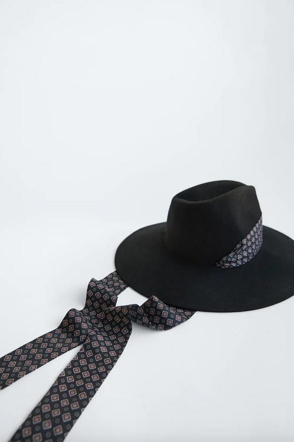 Confeccionado en fieltro con cinta estampada alrededor de la copa y lazada bajo la misma, este sombrero negro de Zara cuesta 26,95 euros y estará disponible en las tallas S y M.