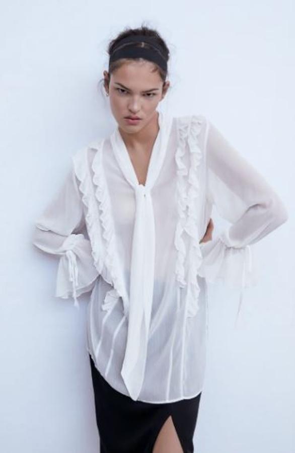Una de las blusas con lazada más originales está en Zara y este modelo largo, con volantes en cuerpo y mangas y transparente (29,95 euros).