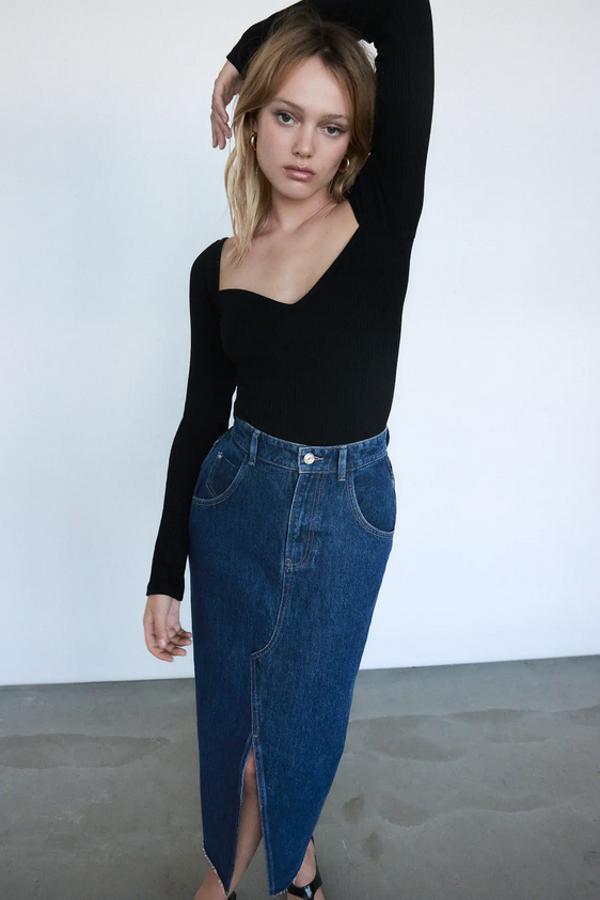 De tiro alto, con efecto lavado y bajo sin costura con abertura frontal, esta falda midi denim de Zara tiene un precio de 25,95 euros y está disponible entre las tallas XS y L.