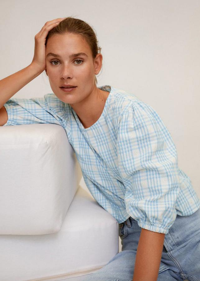 Diseño ancho y cuello redondo para esta blusa de algodón de Mango con detalles elásticos en las mangas cortas con cierre de lazo y dibujo tejido en el frontal. Cuesta 25,99 euros y está disponible entre las tallas XS y L.