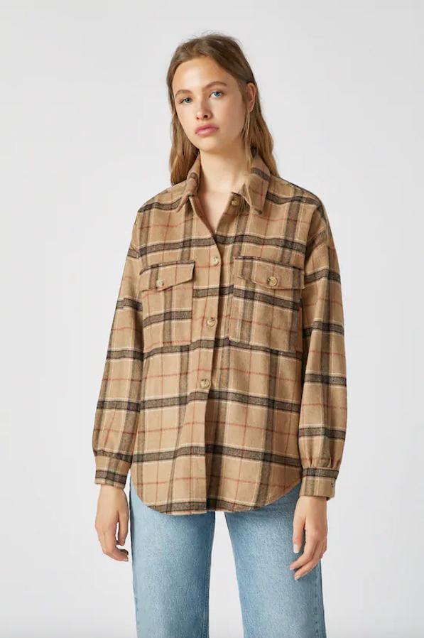 De venta exclusiva en la web de Pull&Bear, esta sobrecamisa de cuadros en tonos beige y negros viene con bolsillos de tapeta en la parte delantera, con cuello clásico y cierre de botones de carey. Confeccionada en mezcla de lana, cuesta 29,99 euros y está disponible en las tallas S, M y L.