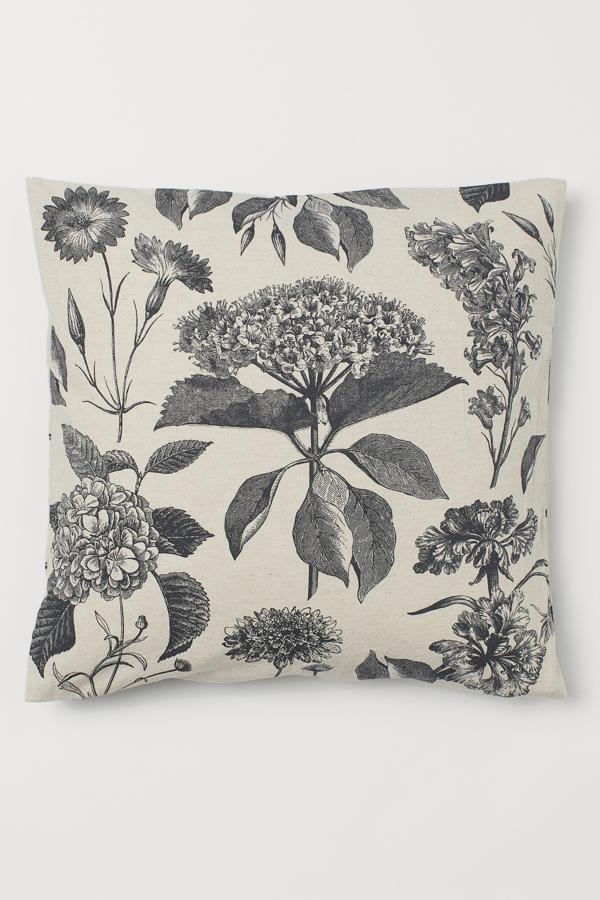 En color gris con estampado floral, esta funda de cojín de algodón orgánico con lino mide 50x50 centímetros y tiene un precio de 7,99 euros.