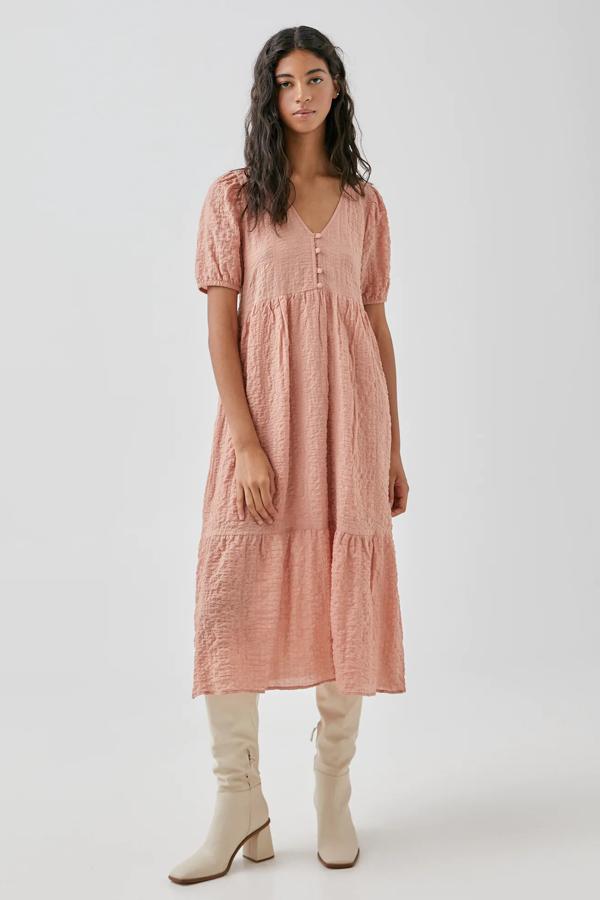 En color rosa, este vestido midi con tejido de textura cuenta con cuello de pico, manga francesa y cierre frontal con botones. Tiene un precio rebajado de 17,99 euros.