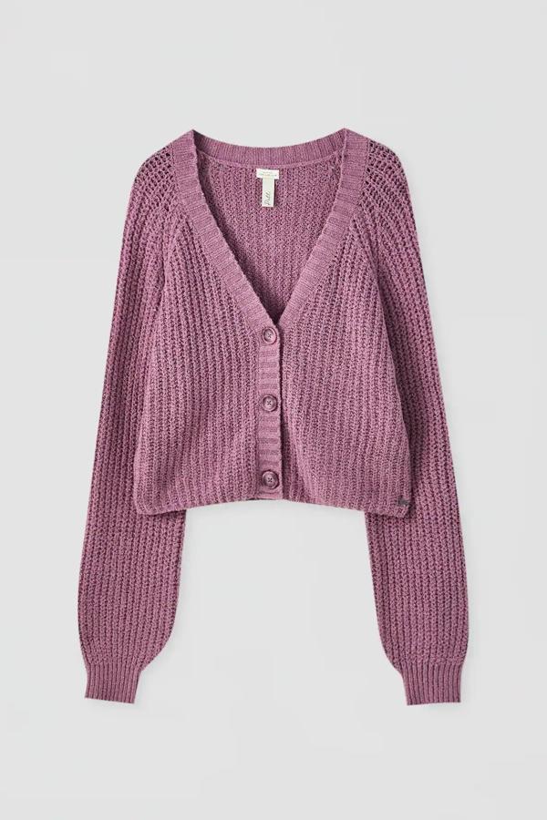 Esta chaqueta de manga larga en tejido de canalé está disponible en malva o en gris. Con escote en forma de pico y cierre mediante botones, es de Pull & Bear y tiene un precio de 22,99 euros.