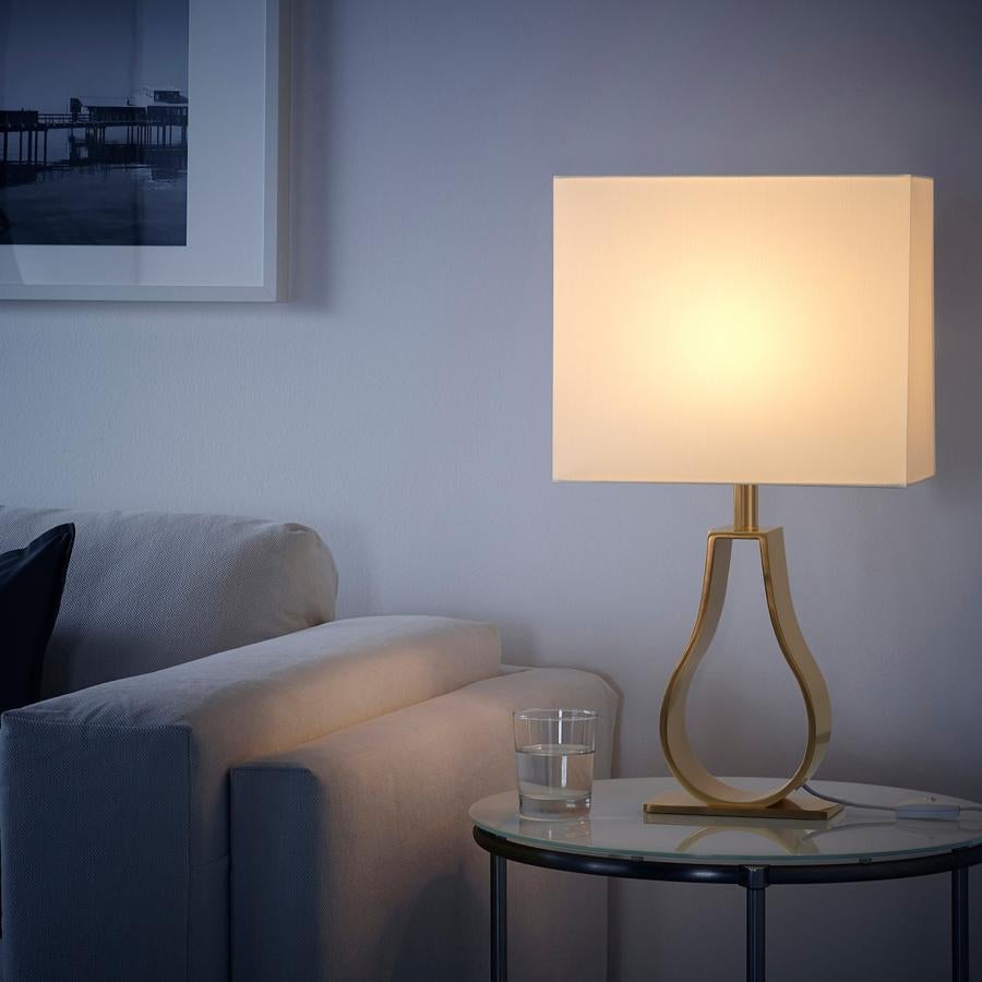 Esta original lámpara de mesa con base de aluminio brillante con forma de lágrima contrasta con la pantalla rectangular de tela en color crema. Tiene unas medidas de 44 centímetros y un precio de 30 euros.