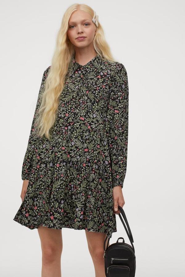 Confeccionado en viscosa, con cuello redondo, botones superiores y mangas largas voluminosas, este vestido negro con estampado floral en tonos lilas y rosas viene con falda con vuelo y fruncido escalonado para un toque extra de volumen. Tiene un precio de 29,99 euros y está disponible entre las tallas 32 y 46.