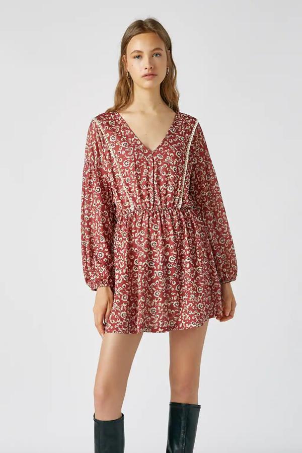 Este minivestido de color granate con estampado tiene manga larga y escote de pico. Con detalle de frunce en la cadera, su precio es de 22,99 euros.