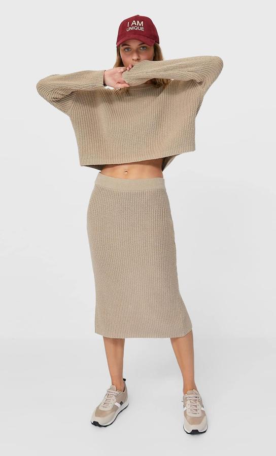 Esta falda midi de punto con tiro alto y cintura elástica cuenta con detalle de abertura en el bajo y es de Stradivarius. En color piedra, tiene un precio de 19,99 euros.