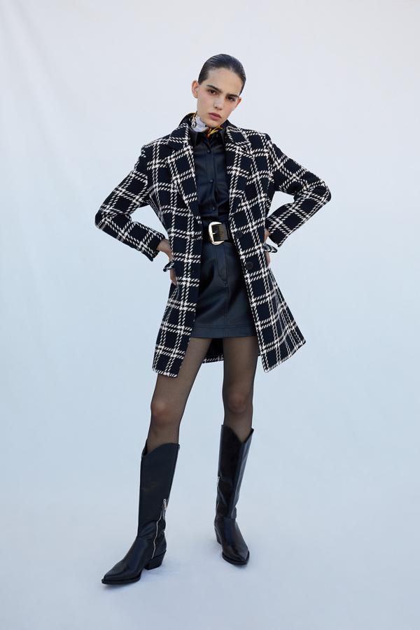 Con diseño de cuadros tartán en color blanco sobre fondo negro, este abrigo de solapas con muesca y bolsillos laterales con solapa de diseño medio es de Sfera y está disponible en las tallas S, M y L por 69,99 euros.