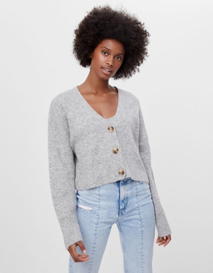 En Bershka hemos encontrado este conjunto de top y cárdigan en color gris. El primero viene con tirantes, diseño cropped y bajo acanalado por 12,99 euros y la segunda llega con mangas largas, cuello de pico y cierre de botones de carey por 19,99 euros. Ambos están disponibles entre las tallas XS y L.