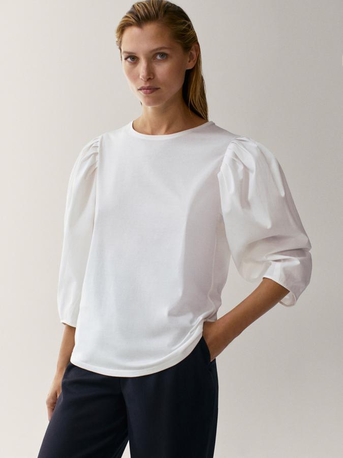 En tejido de popelín confeccionado en algodón, esta camiseta de corte recto y cuello redondo en color blanco tiene las mangas largas abullonadas y es de Massimo Dutti. Cuesta 25,95 euros y podemos encontrarla también en color negro entre las tallas XS y XL.