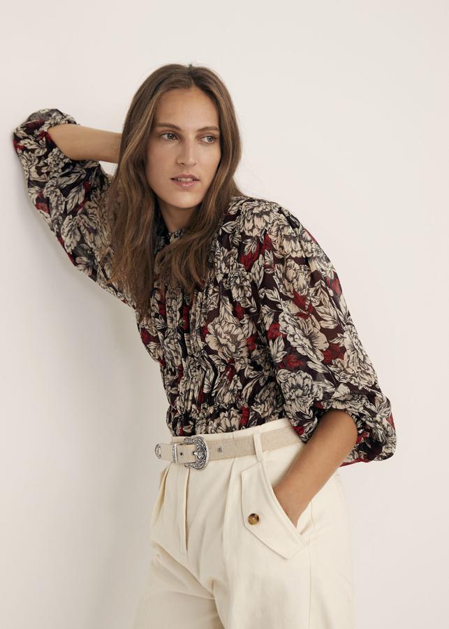 Fondo negro con flores en tonos rojos y blancos para esta blusa de Mango de tejido fluido con diseño plisado, cuello redondo y mangas largas abullonadas acabadas en puños elásticos. Cuesta 29,99 euros y está disponible entre las tallas XS y XL.
