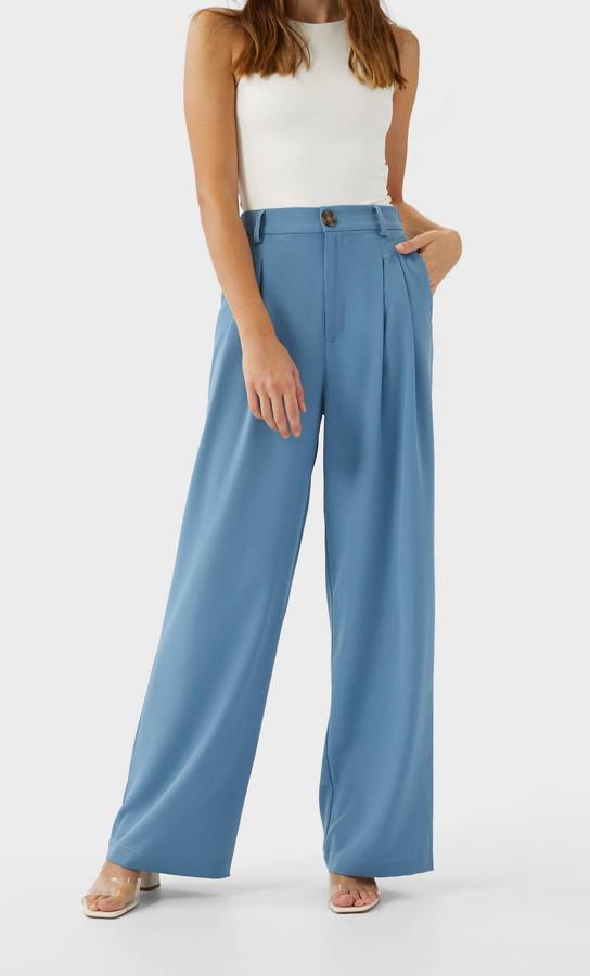 Perneras anchas y detalle de pinzas delanteras para este pantalón recto de Stradivarius en color azul que viene con bolsillos delanteros y cierre frontal de cremallera y botón. Cuesta 19,99 euros y está disponible entre las tallas XS y XL.