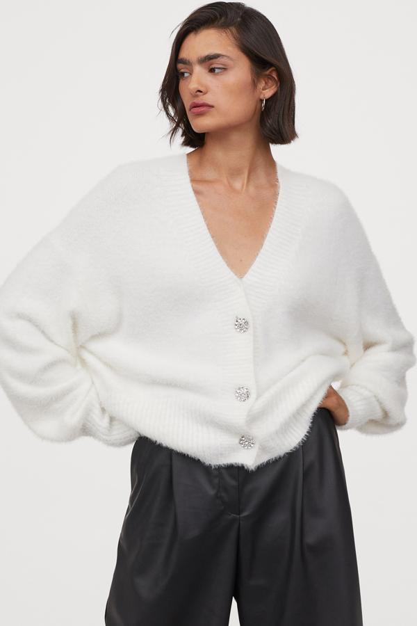 Este cárdigan blanco en punto suave de pelo con escote de pico y botones revestidos de strass cuenta con mangas amplias y tiene un precio de 29,99 euros. Es de H&M.