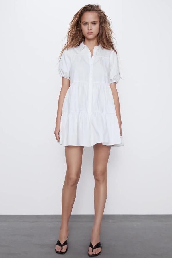 Con cuello redondo y manga corta abullonada acabada en elástico, este vestido blanco con bajo acabado en volante tiene un precio de 25,95 euros y es de Zara.