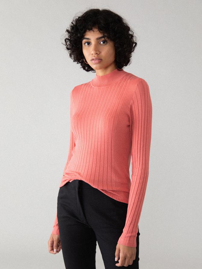 Con cuello ligeramente subido este jersey en rosa salmón de Lefties está confeccionado en punto fino de canalé y tiene un precio de 8,99 euros. Está disponible entre las tallas XS y XL.