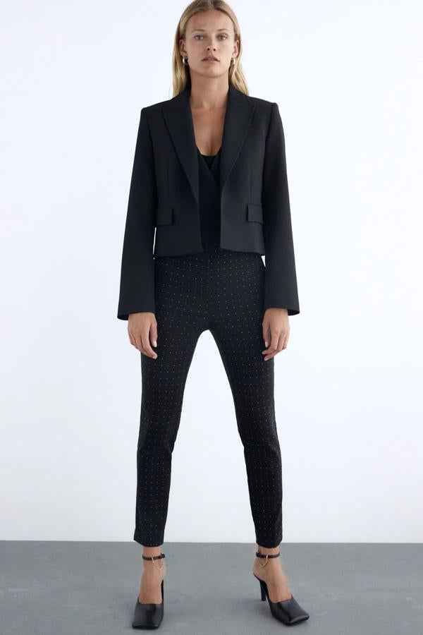 Este pantalón pitillo de tiro alto y tejido Jacquard de lunares en color negro es de Zara y tiene un precio de 25,95 euros.