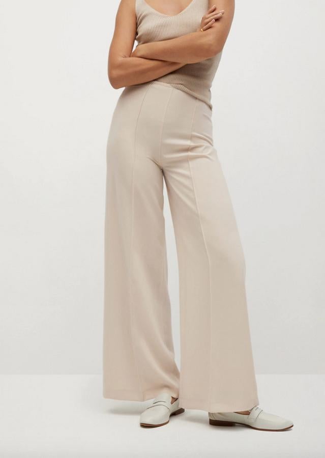 De venta exclusiva en la web de Mango, este pantalón beige de tiro alto y corte palazzo con detalle de pinzas también podemos encontrarlo en color negro entre las tallas 32 y 44 por un precio de 39,99 euros.