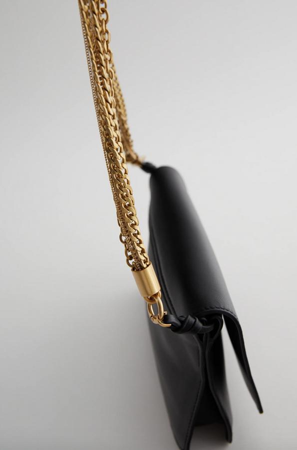 Cuerpo de piel y asa de hombro con cadenas de diferentes grosores en dorado para este bolso negro con cierre de solapa y asa de hombro ajustable y extraíble para convertirlo en bandolera. De 59,95 euros ha pasado a costar 39,99 euros.