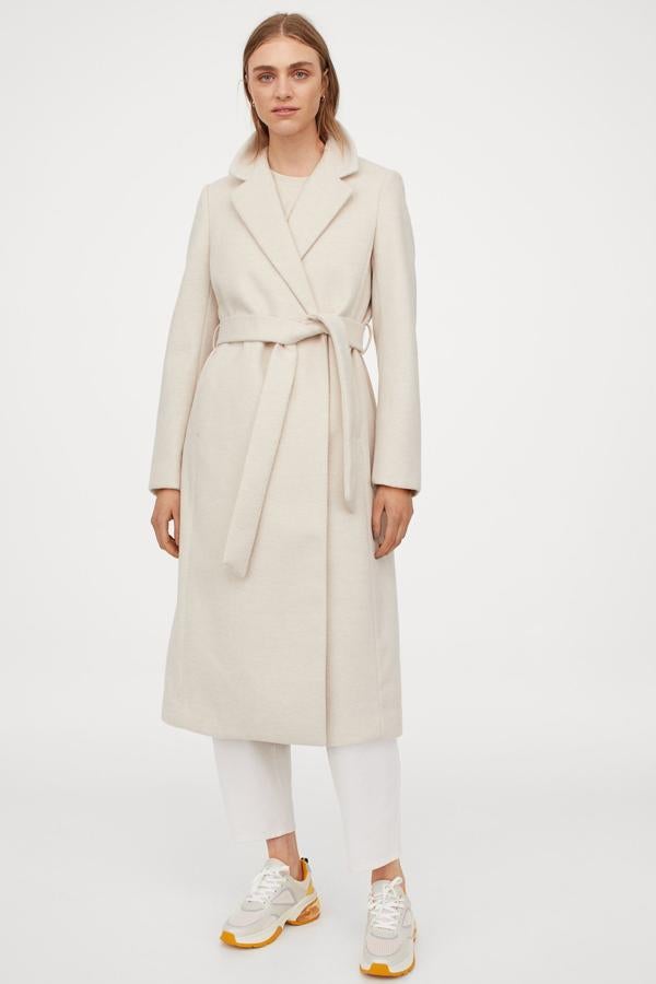 El clásico abrigo midi con cinturón, en blanco roto, de H&M (49,99 euros).