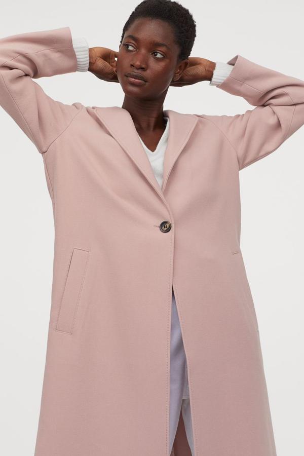 Con cierre de un único botón, este abrigo de H&M en tejido suave, de corte recto con solapas de muescar y bolsillos al bies ribeteados está disponible en rosa pálido, negro, crudo y azul. Confeccionado con poliéster reciclado, podemos comprarlo por 49,99 euros entre las tallas XS y XXL.