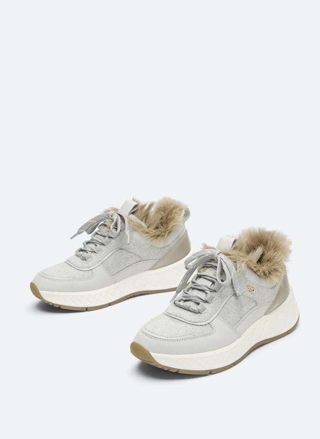 Corte de tejido e inserciones de piel de vacuno para estas deportivas en color gris con forro de pelo de cordero en el tobillo en tonos beige. Con cierre de cordones en gris y tirador en la lengüeta, cuestan 99 euros y están disponibles entre los números 35 y 39 y en el 42.