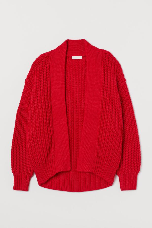 En color rojo, este cárdigan en punto de canalé suave cuenta con mangas extralargas y solapas en punto liso. Tiene un precio de 29,99 euros.