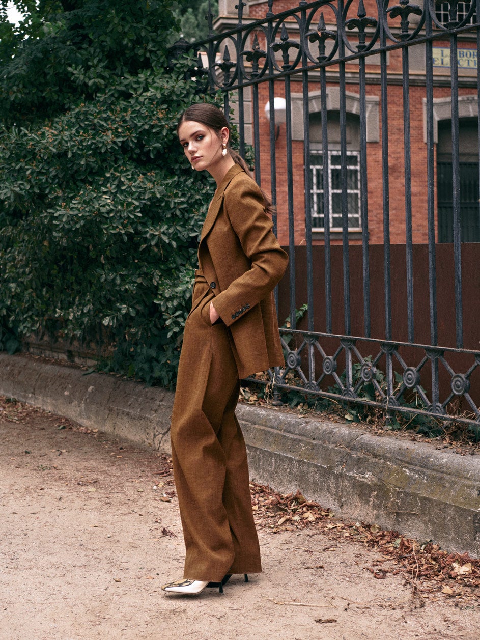 Americana, pantalón con fajín de botones y top, todo en lana, de Salvatore Ferragamo. Mules de piel bicolor y serpiente, de Jimmy Choo; y pendientes de oro con perlas, de Aristocrazy.