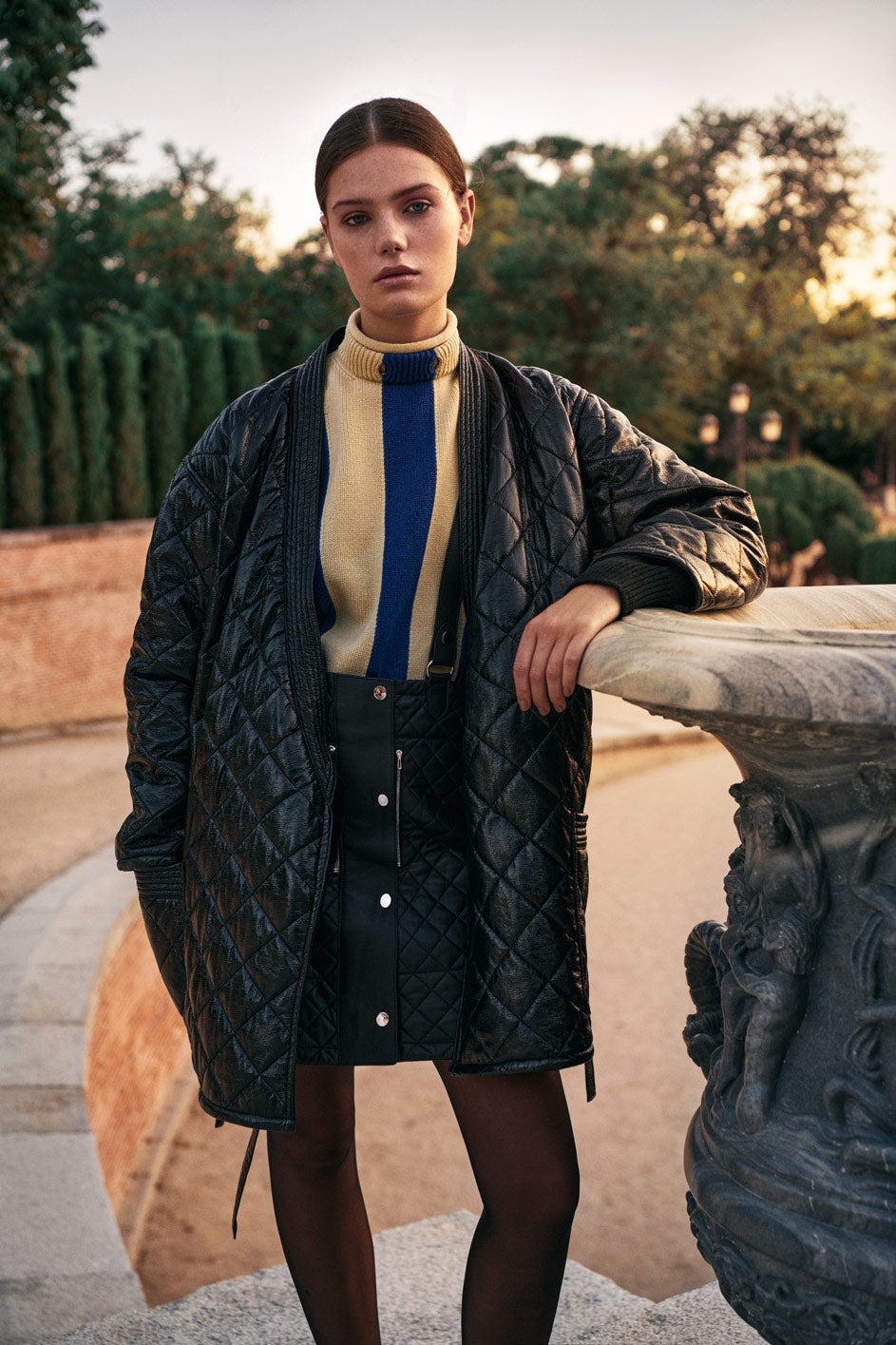 Abrigo acolchado de piel ecológica, de Philosophy di Lorenzo Serafini. El jersey de lana y cachemir, y la falda con tirantes de napa acolchada son de Hermès. Medias de El Corte Inglés.