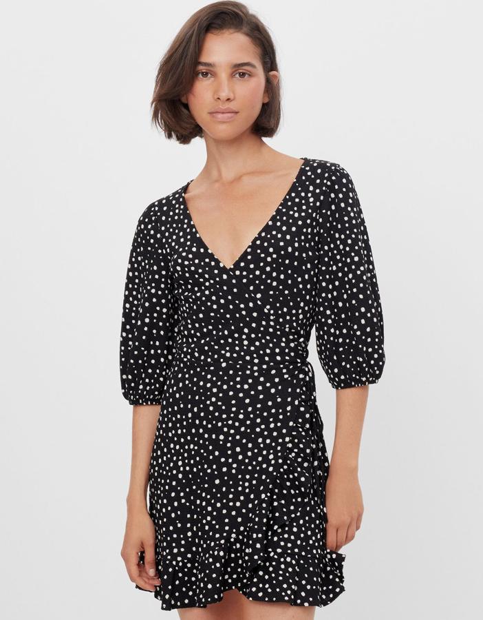 Este vestido cruzado en color negro con topos blancos cuenta con volante en el bajo y manga a la altura del codo. Tiene un precio de 11,99 euros.