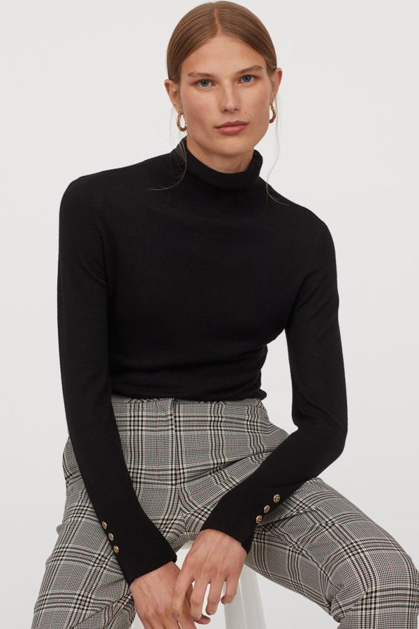 De cuello alto, en punto fino y suave con lana en la trama, este jersey disponible en crema y beige oscuro tiene las mangas largas con botones decorativos dorados en los puños. Con cuello, puños y bajo en punto de canalé, tiene un precio de 19,99 euros y está disponible entre las tallas XS y XXL.