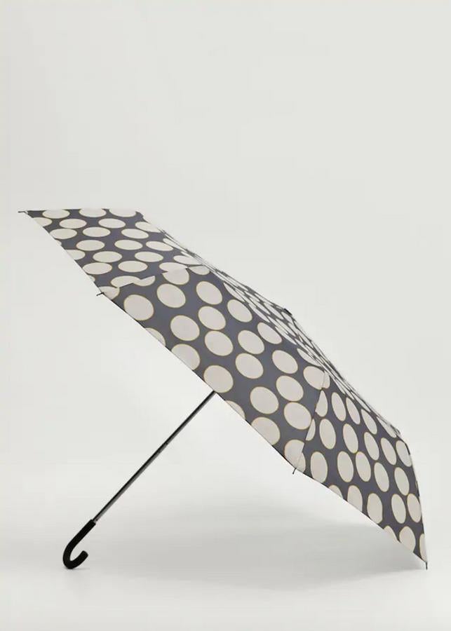 Estampado de lunares en tonos grises y blancos con mostaza para este paraguas plegable de Mango que tiene un precio de 12,99 euros y viene con funda a juego.
