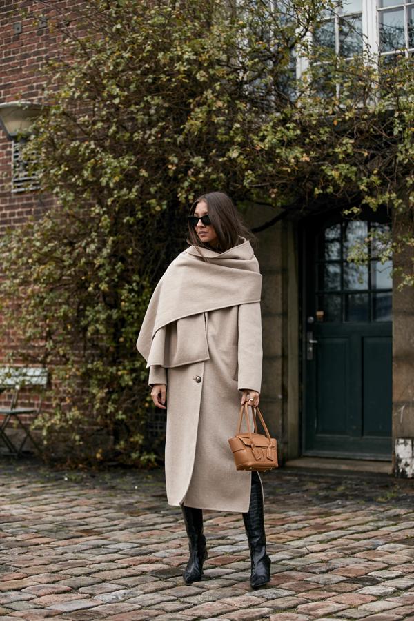Un look básico que nunca falla: abrigo largo de lana y botas altas. Los tonos neutros mandan en este estilismo que funciona 24/7. Pero, ¿qué lo convierte en algo especial? Un toque tan sencillo como el chal, que aporta sofisticación y elegancia al conjunto.