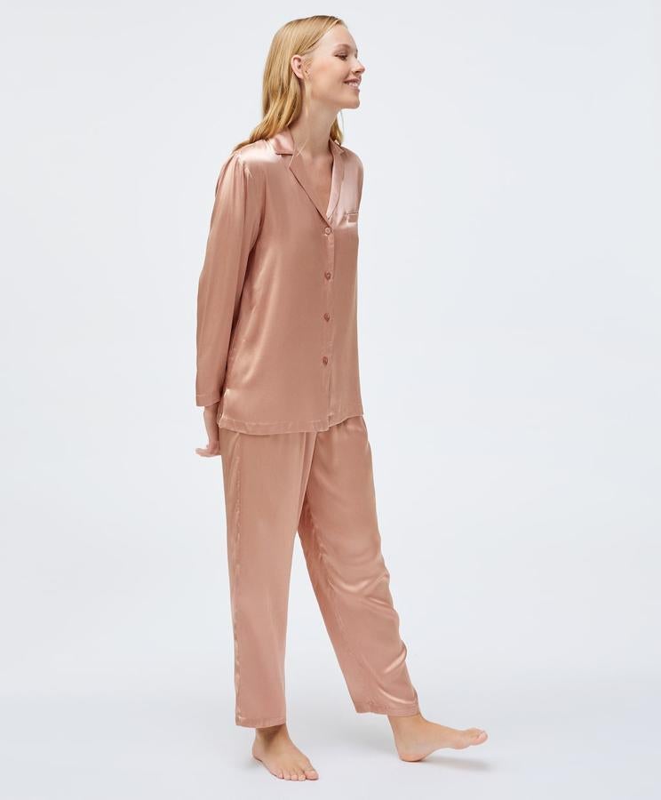 Diseño camisero para este pijama de Oysho en color rosa con cierre de botones frontal y bolsillo lateral en la parte superior y pantalón largo con cintura elástica. Tiene un precio de 48,98 euros y está disponible entre las tallas XS y XL.